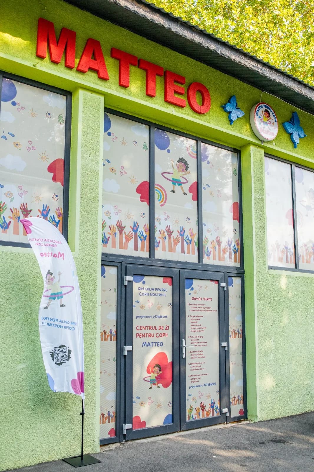 Fațada verde a centrului, cu literele Matteo, ferestre decorate și ușa de intrare.