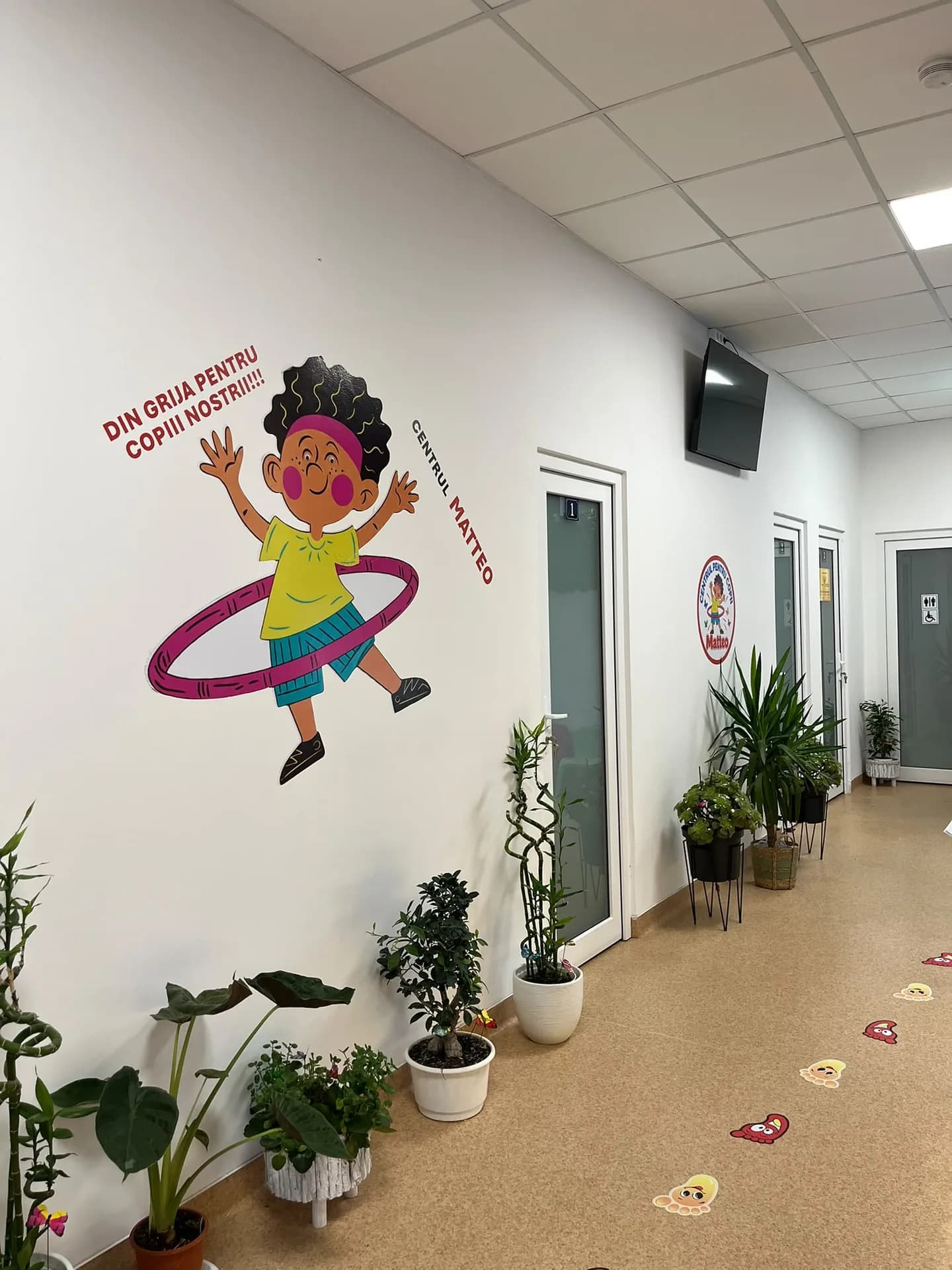 The Matteo mascot on the hallway wall beside plants and room doors.