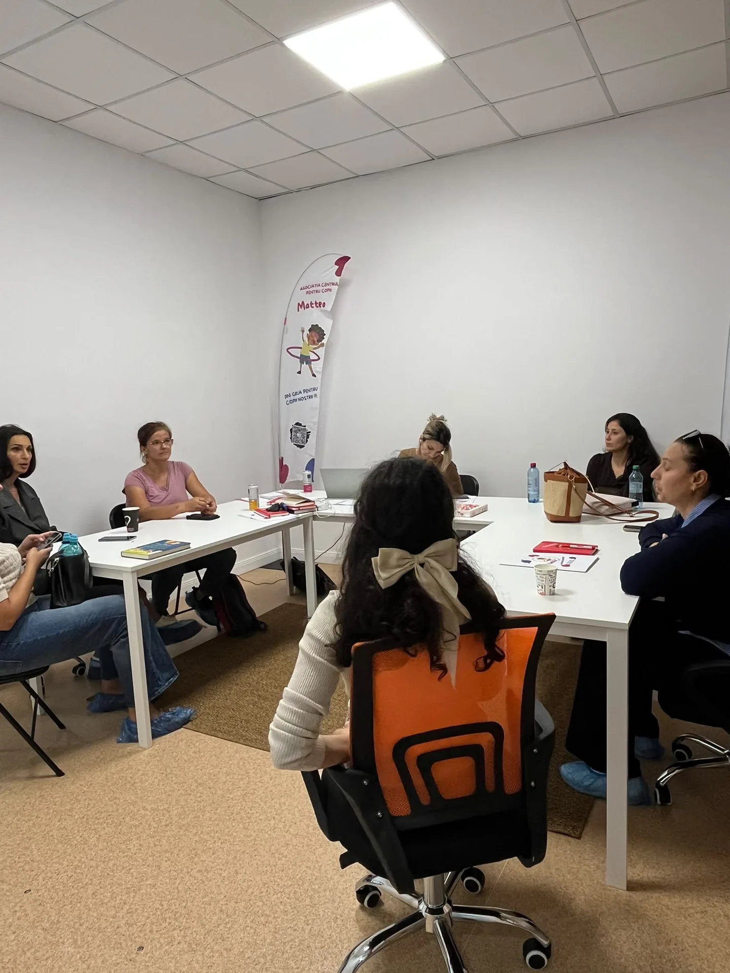 Adults gathered in the center’s meeting room with a Matteo flag in the background.