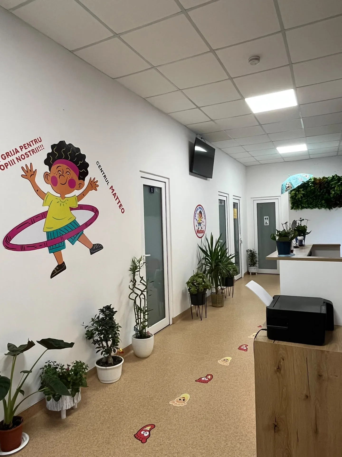 The Matteo Center hallway with plants, room doors and the reception desk.