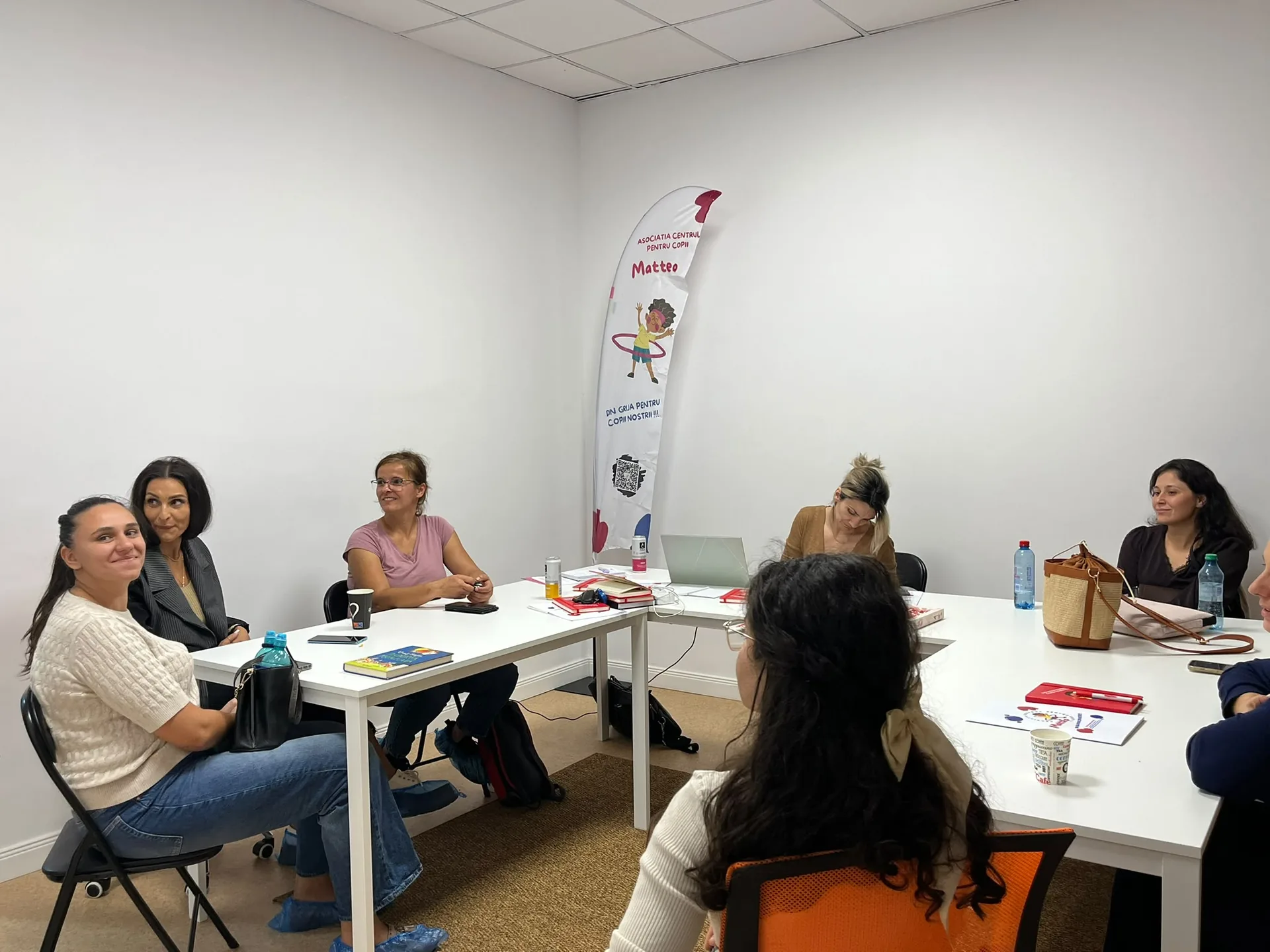 People talk around white tables with notebooks and Matteo materials within reach.