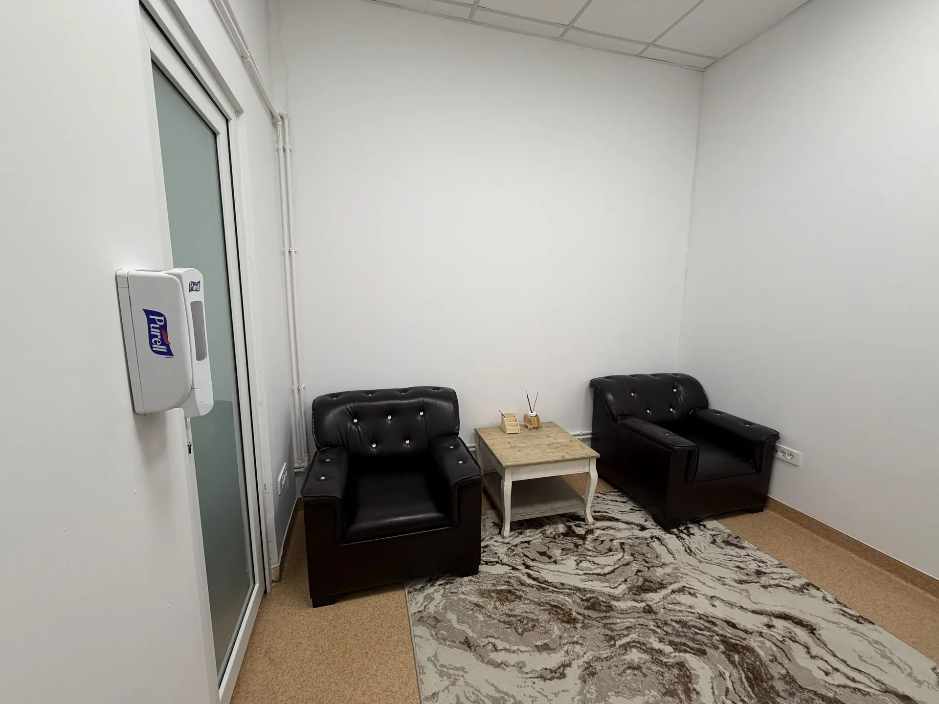Two black armchairs and a small table in a room with a light-colored rug.
